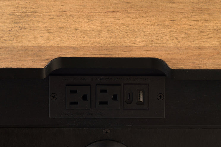 Black power strip with multiple outlets and a USB port on a wooden surface